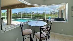 A covered patio with a pool, a table, and chairs. - Turtle Bay, heated pool, 2 dogs ok, pool table (Rotonda West)