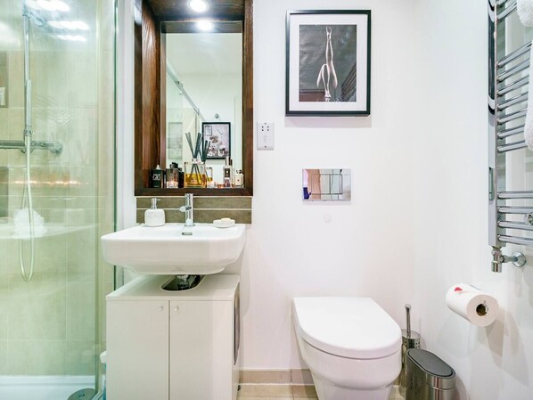 A modern bathroom with a glass shower enclosure, a white sink with a mirror above, a toilet, and a framed picture on the wall. - Cathedral Quarter | City Centre | Walk Everywhere - Pass the Keys (Belfast)