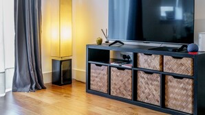 A modern living room with a large flat-screen TV, a floor lamp, and a herringbone-patterned storage unit. - Cathedral Quarter | City Centre | Walk Everywhere - Pass the Keys (Belfast)