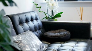 A black leather sofa with a sequined pillow and a dark cushion, a small potted orchid, and a picture frame on a shelf. - Cathedral Quarter | City Centre | Walk Everywhere - Pass the Keys (Belfast)