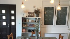 A dining area with a table and chairs, a bookshelf, and a door with windows. - A beautiful olive orchard with mountain and sea view,ideal for a relaxing break  (Ziria)