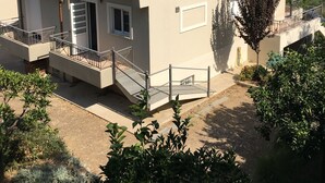 A two-story building with a red-tiled roof, a balcony, and a small garden area. - A beautiful olive orchard with mountain and sea view,ideal for a relaxing break  (Ziria)