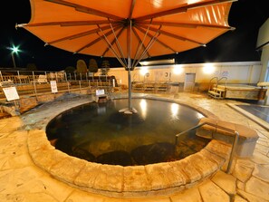 A hot spring bath area with a large umbrella, stone steps, and a wooden platform. - HigashimaeOnsen Hotel Akitaya (Hokuto)