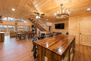 A spacious wooden interior with a large dining table, a staircase, and a television mounted on the wall. - Outdoor Fireplace * Mountain Views * Hot Tub * (Mineral Bluff)
