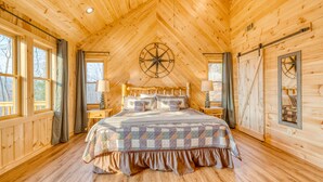 Une chambre aménagée dans un chalet en rondins, avec un grand lit, une décoration murale représentant une boussole et un plafond en bois.