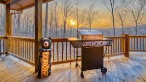 Une terrasse en bois avec un barbecue et un panneau d’accueil en forme d’ours.