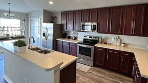 A modern kitchen with dark wooden cabinets, stainless steel appliances, and a central island with a sink.