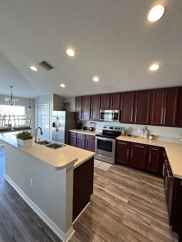 A modern kitchen with dark wooden cabinets, stainless steel appliances, and a central island with a sink.