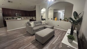 A modern living room with a sectional sofa, ottoman, and a ceiling fan.