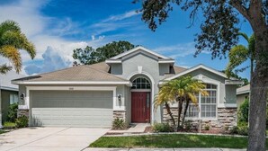 A two-story house with a garage, a red door, and a well-maintained lawn.