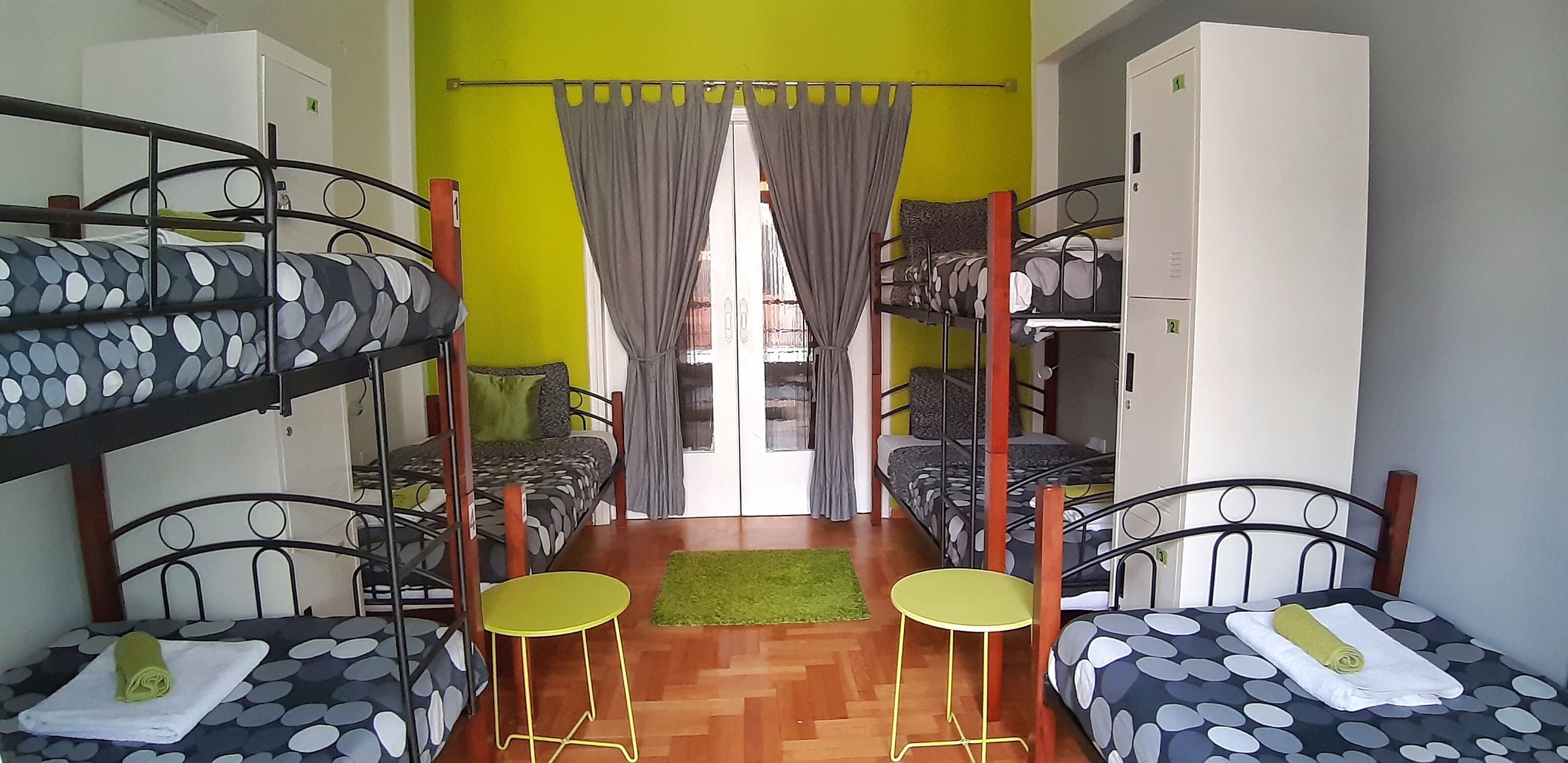 A dormitory room with bunk beds, a small table, and a chair.