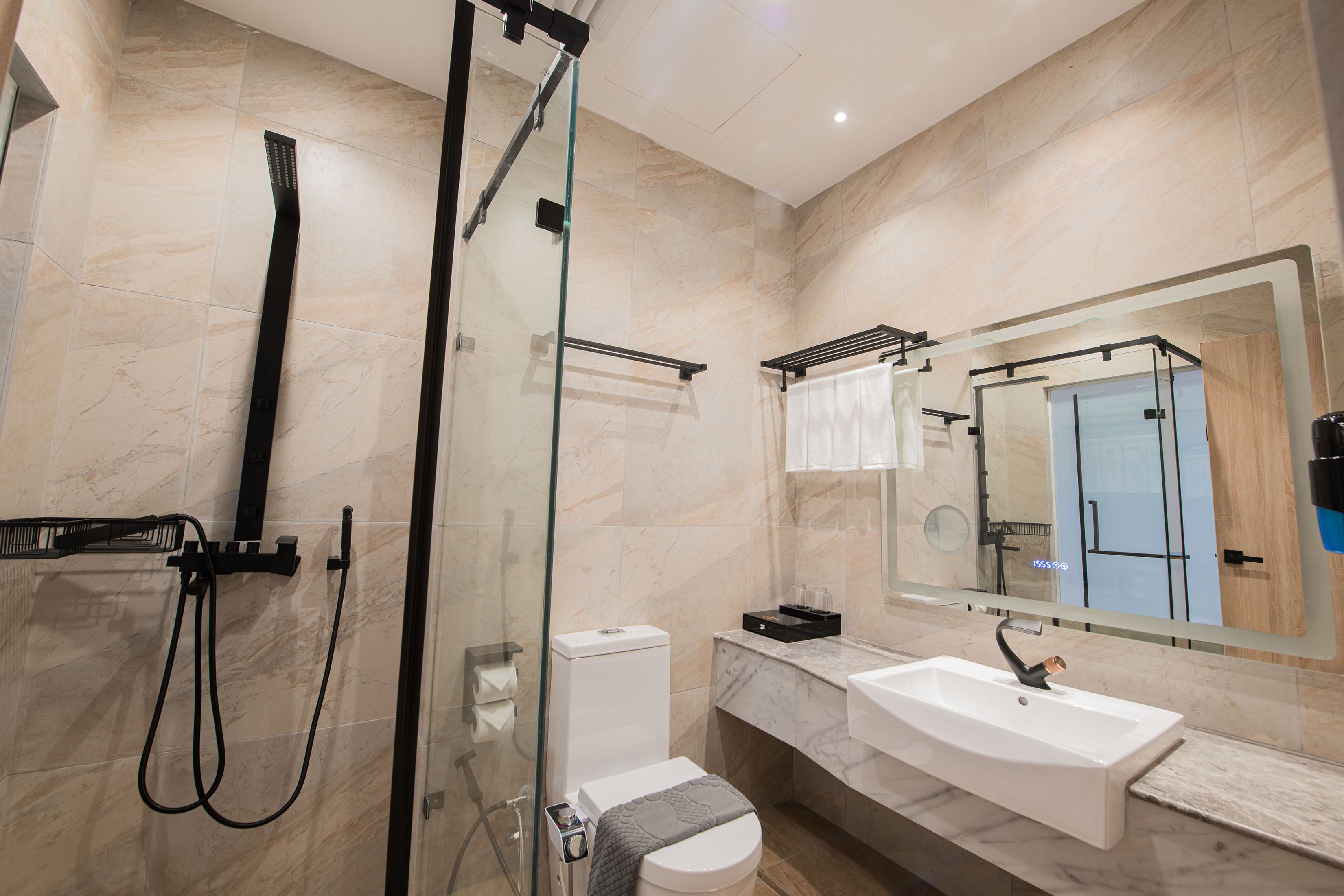 Un baño moderno con cabina de ducha de vidrio, un lavabo blanco y un espejo grande.
