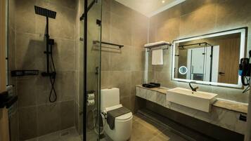 A modern bathroom with a glass-enclosed shower, a white toilet, a vanity with a mirror, and a sink.