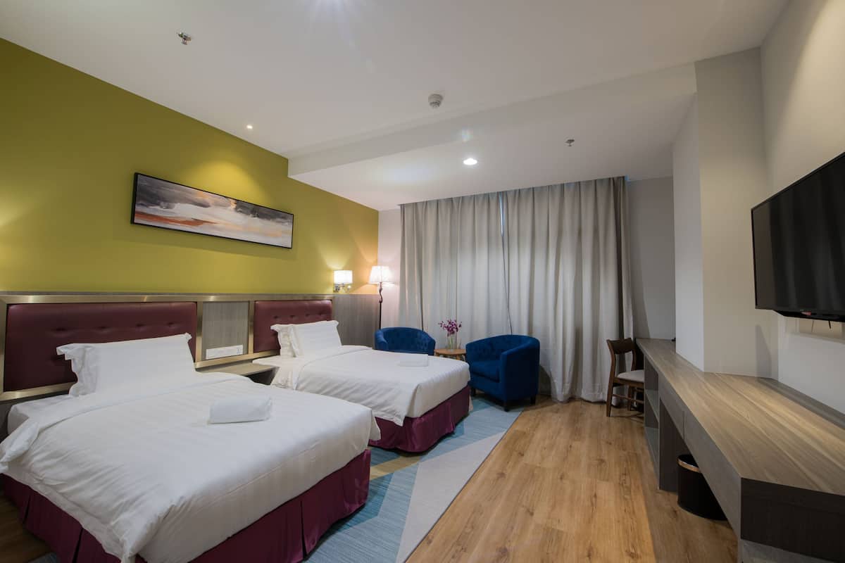 A hotel room with two beds, a desk, a chair, a TV, and a painting on the wall.