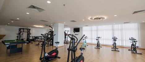 A spacious gym with various exercise equipment, including treadmills and stationary bikes, and a pool table.
