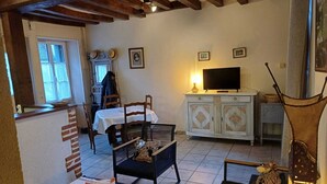 Una habitación acogedora con una mesa de comedor, sillas, televisión y un armario.