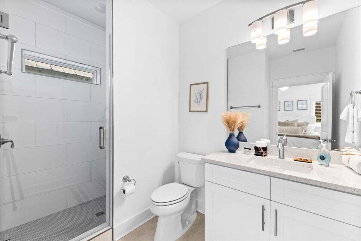 A modern bathroom with a glass shower enclosure, a white toilet, and a vanity with a mirror.