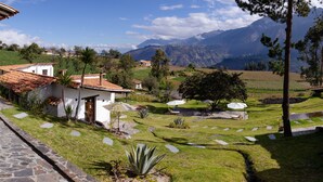 Una casa con techo de tejas, un sendero de piedra y un patio con césped con vistas a montañas.