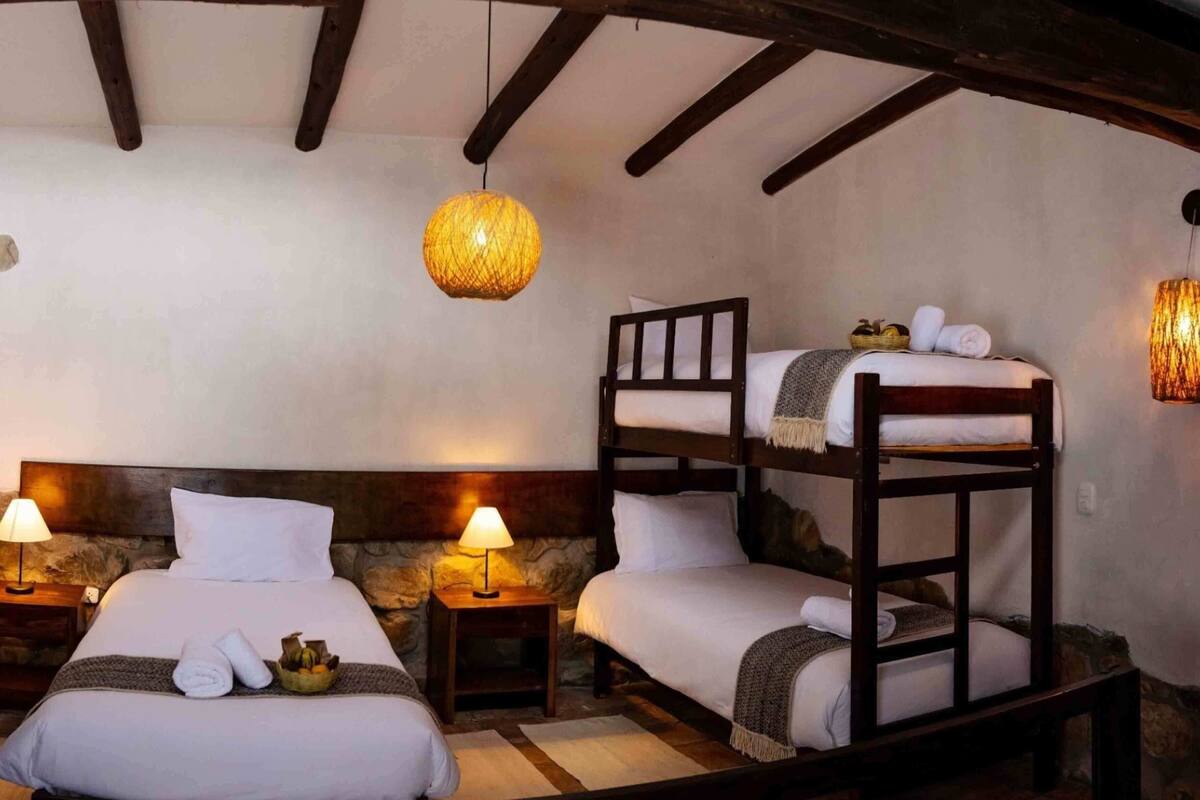 A cozy room with two beds, a stone wall, and a wooden ceiling.