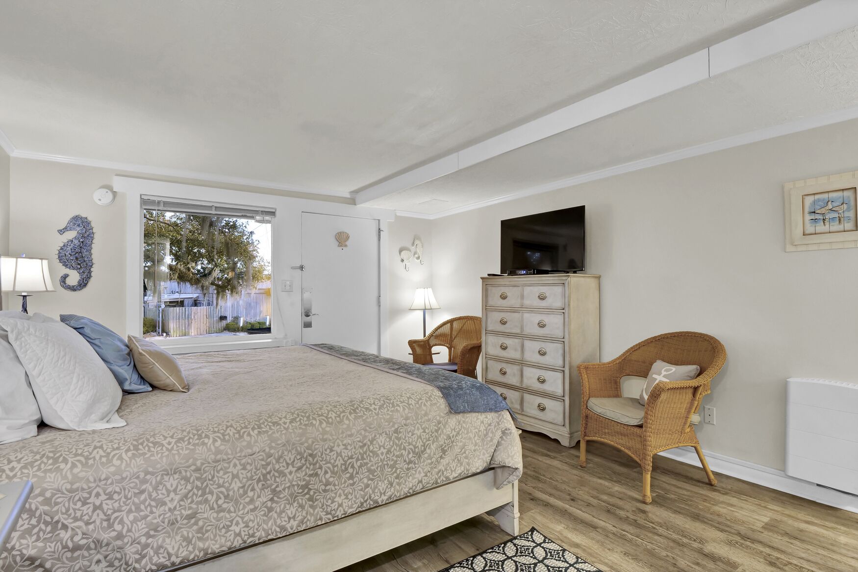 A bedroom with a bed, dresser, chairs, and a TV.