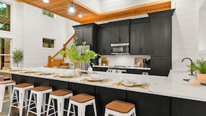 Una cocina moderna con armarios oscuros, una isla grande con taburetes de bar y un techo de madera.