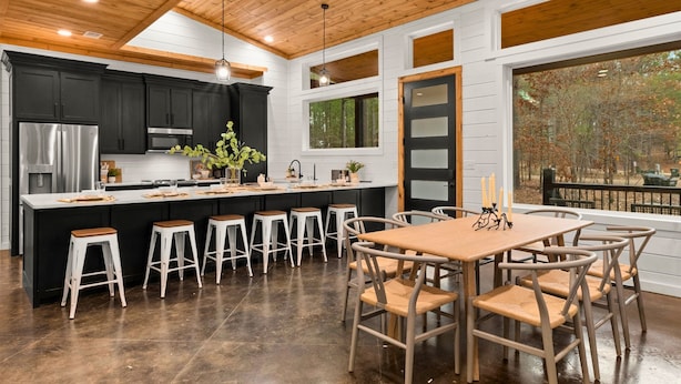 Una cocina moderna con una isla central, taburetes de bar y una mesa de comedor con sillas.
