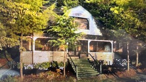 A house with a sloped roof, a front porch, and a staircase leading to the entrance.