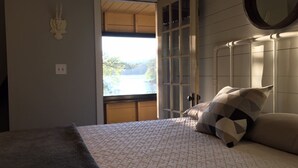 A bedroom with a bed, a window, and a view of a lake.
