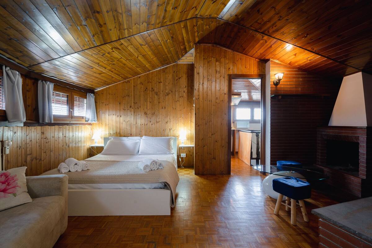 Una cabaña de madera con un dormitorio en el entrepiso, una chimenea y una zona de estar acogedora.