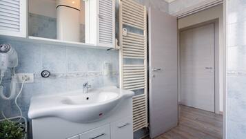 Une salle de bain avec un lavabo blanc, un porte-serviettes et une porte.