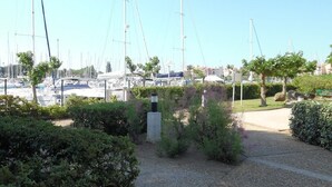 Una marina con diverse barche a vela ormeggiate, immersa nel verde e con una passeggiata lastricata.