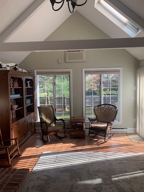 A spacious room with a sloped ceiling, large windows, and a wooden bookshelf. - Blissful Vacation Experience! Spacious, fully fenced house with backyard oasis! (Yarmouth)