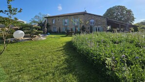 Une maison en pierre avec une pelouse et un jardin bien entretenus.