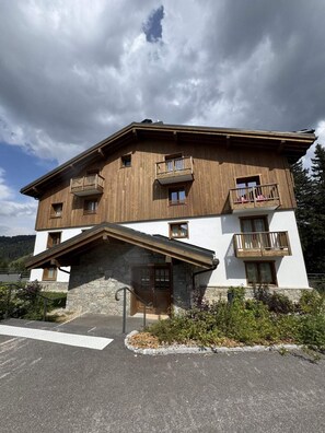 A multi-story building with wooden balconies, a stone entrance, and a clear sky.
