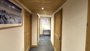 A narrow hallway with wooden doors and a tiled floor, leading to a room with a desk and a framed picture on the wall. - 250m from ski slopes, Ground floor, terrace, parking, tv, ski locker, 72m², Les Saisies (Villard-sur-Doron)