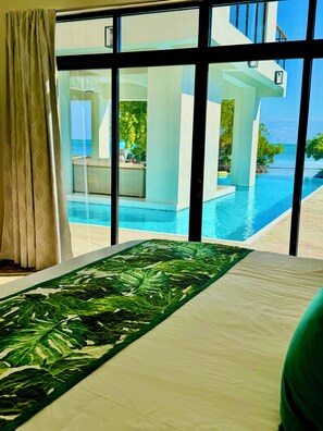 A room with a large window overlooking a pool and a view of the ocean. - Oceanfront 5 bedroom Hibiscus House Private Villa Beach BEST Pool on the Island (San Pedro)