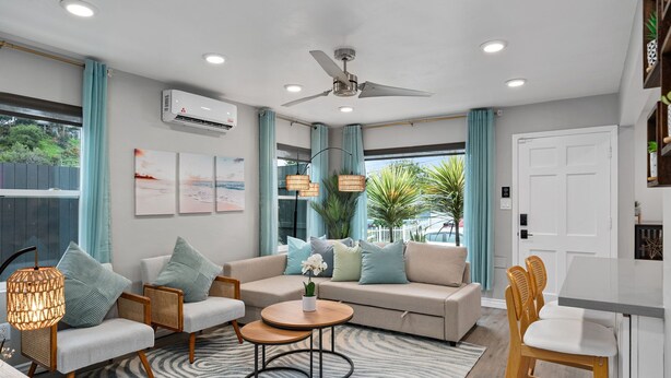 A modern living room with a sofa, chairs, a coffee table, and a dining area.