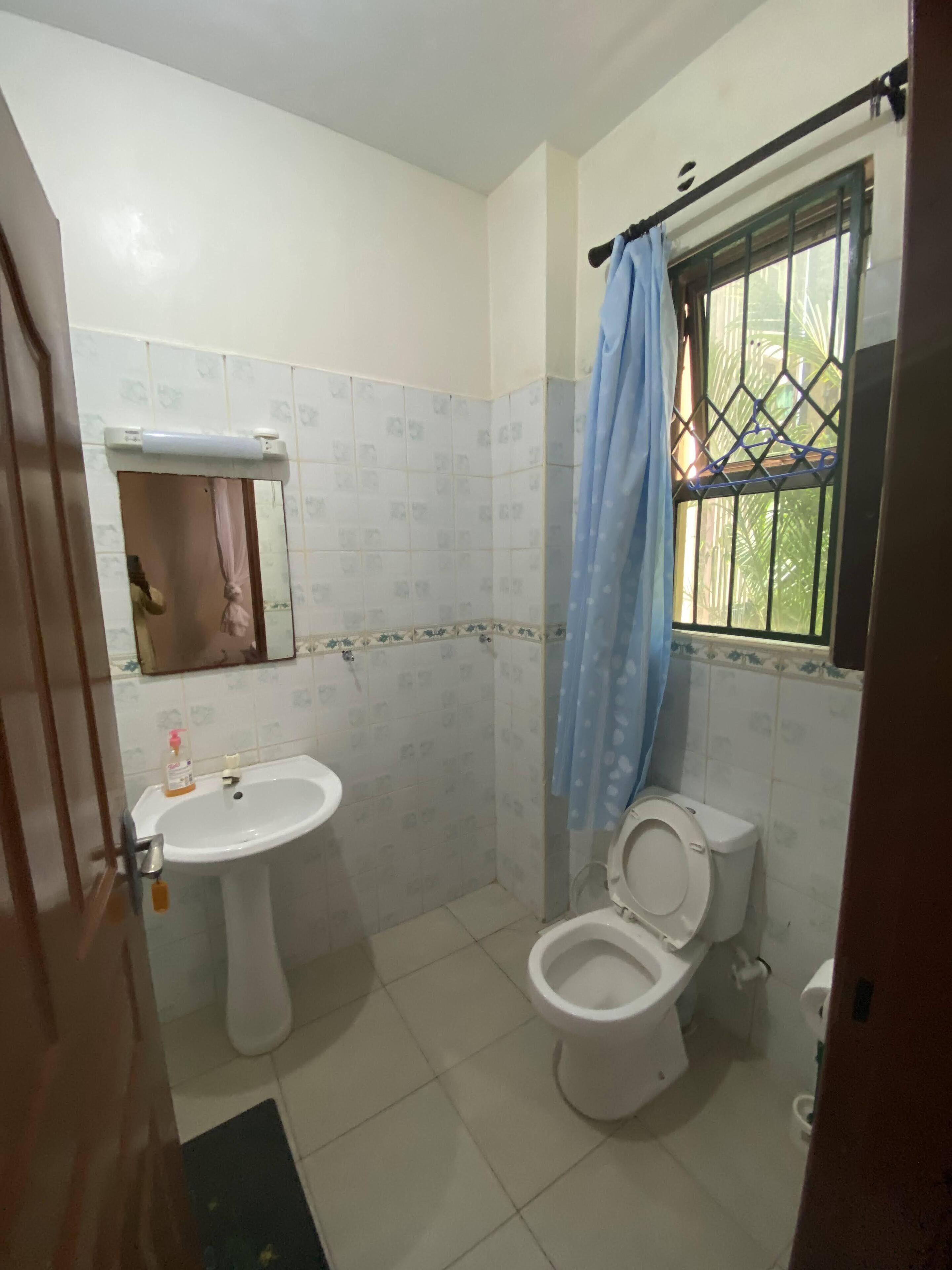 Un baño pequeño con lavamanos, inodoro y ventana con reja de metal.