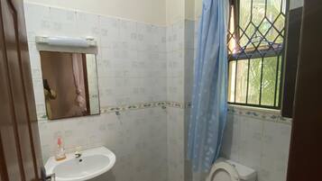 A small bathroom with a sink, toilet, and a window with a metal grill.