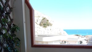 A balcony with a wooden table and chair, overlooking a coastal area with buildings and the sea. - Attic room with terraces facing the sea, close to the beach and Scala dei Turchi (Lido Rossello)