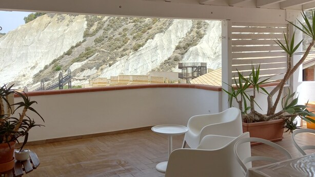 A balcony with white chairs and a table, overlooking a mountainous landscape. - Attic room with terraces facing the sea, close to the beach and Scala dei Turchi (Lido Rossello)