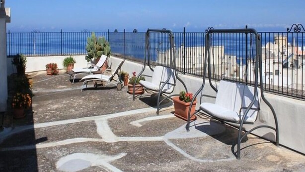 A terrace with outdoor seating and a view of the sea.