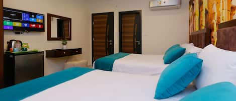 A hotel room with two beds, a TV, a desk, and an air conditioner.
