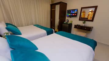 Een hotelkamer met twee bedden, een televisie, een bureau met een plant en een kledingkast.