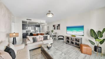 A modern living room with a sofa, coffee table, and a TV mounted on the wall.