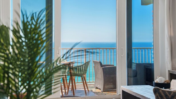 Ein Balkon mit Meerblick, einem Tisch, Stühlen und einem Blumentopf.