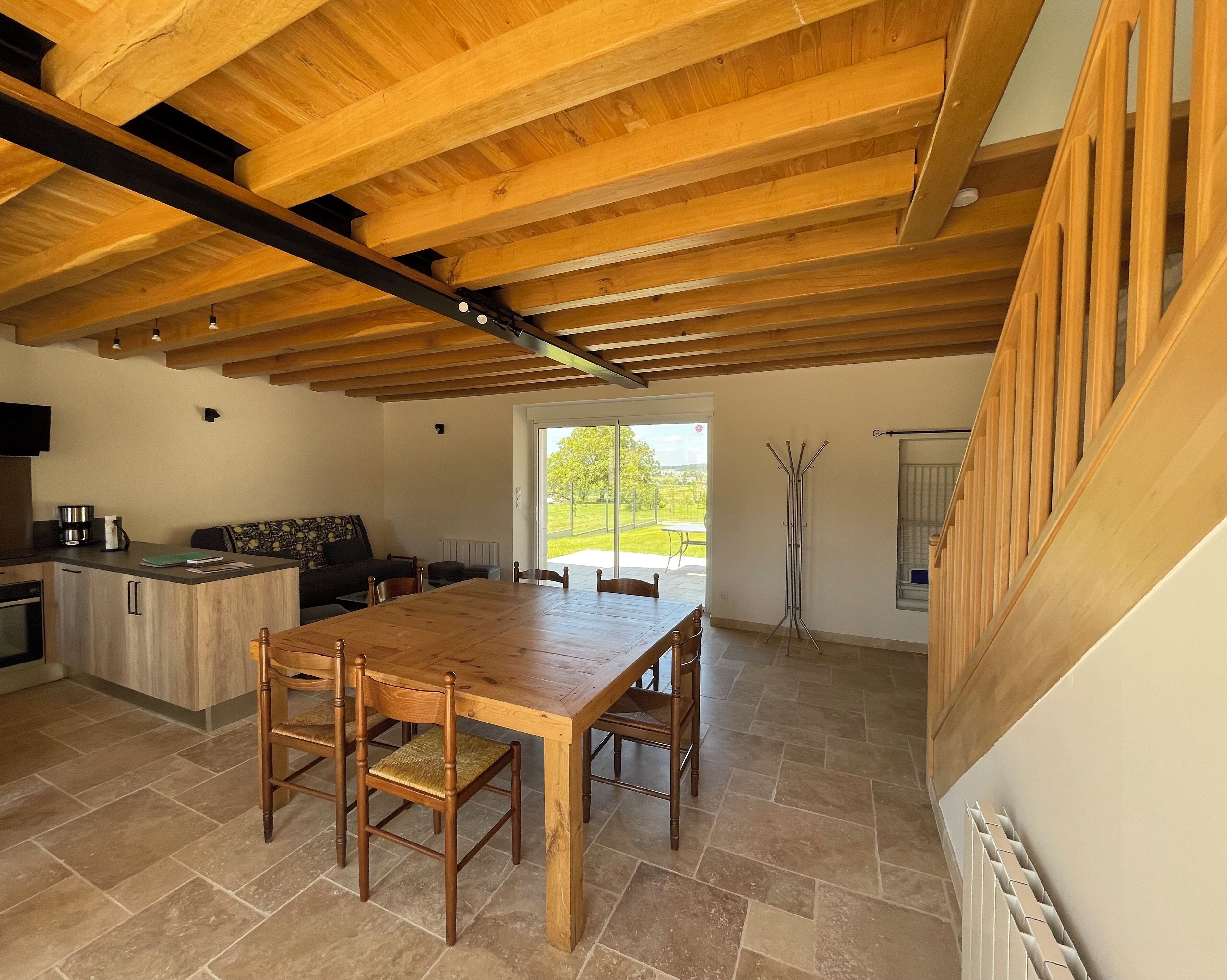 A spacious kitchen with a wooden table and chairs, a built-in oven, and a large window providing a view of the outdoors.