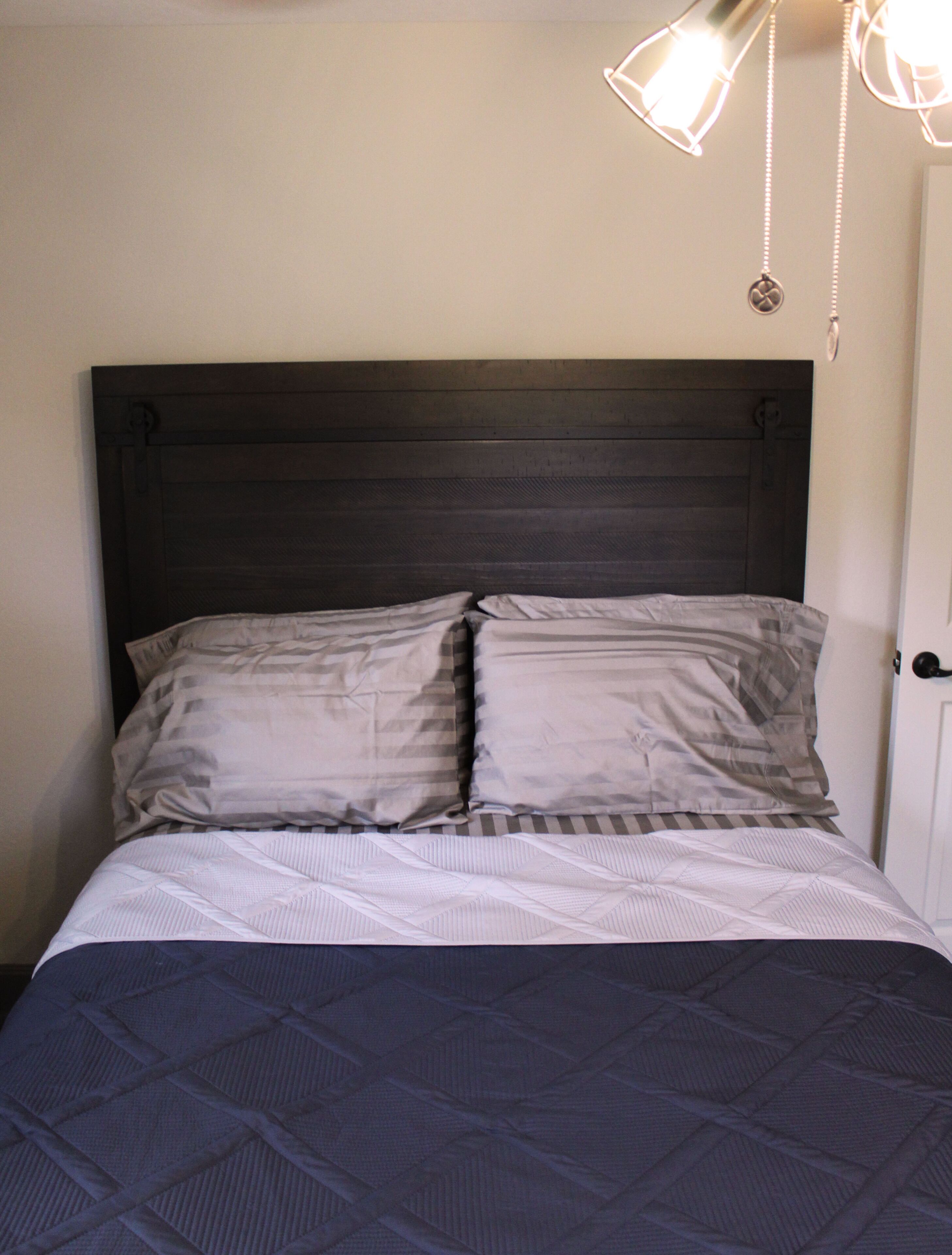 Un letto con una testata scura, due cuscini e una coperta a fantasia.