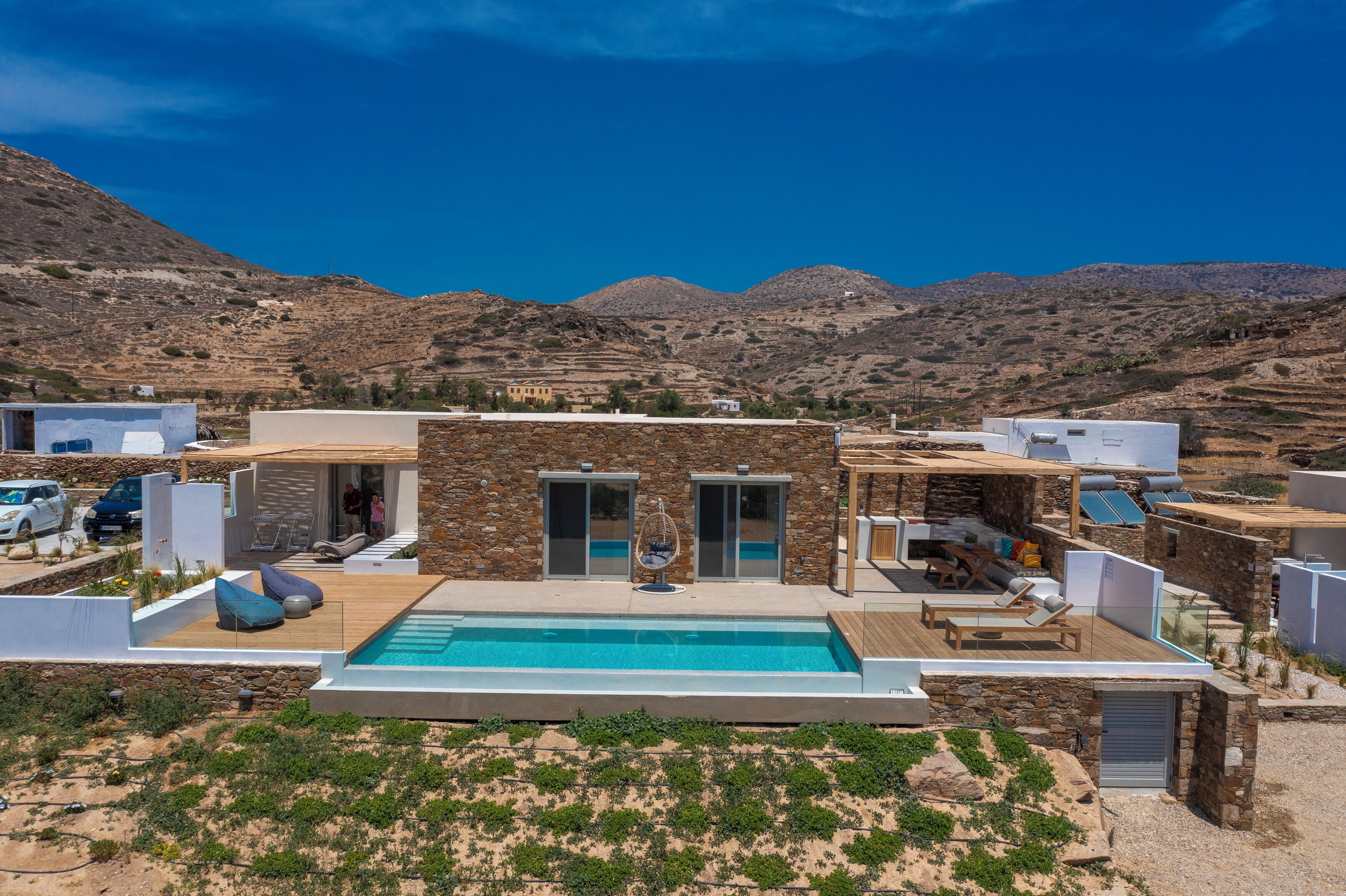A modern villa with a swimming pool, stone walls, and a view of the mountains.