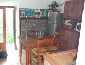 Compact kitchen with dining area, refrigerator, microwave, and potted plant.